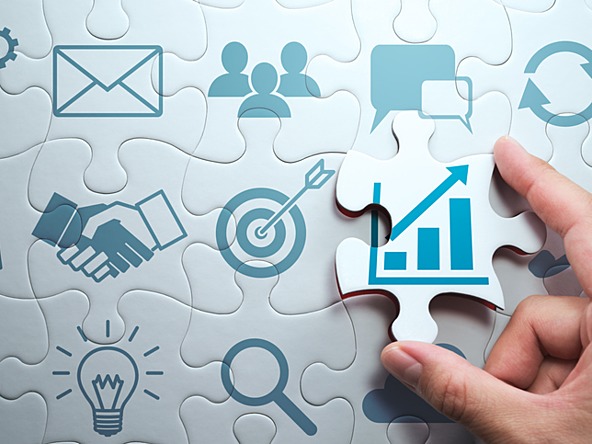 Jigsaw with various business icons, including graph portraying revenue growth